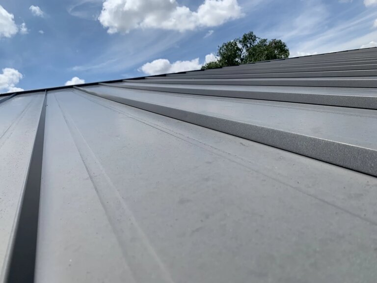 Clean gray standing seam metal roof panels with sky background — 5 Star Roofing premium hail protection