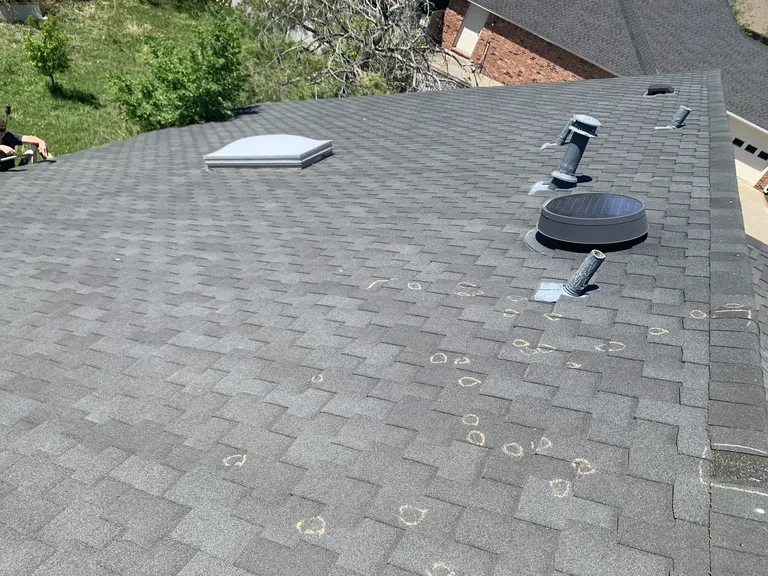 Hail-damaged residential shingle roof showing impact marks and chalk-circled damage points — 5 Star Roofing inspection